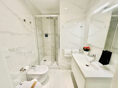 Bagno moderno nel St Mary Major Loft Roma con pareti in marmo, doccia in vetro, lavabo bianco, wc e bidet