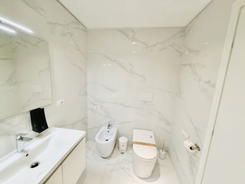 Bagno moderno dello St Mary Major Loft Roma con pareti in marmo, lavabo, bidet, wc e doccia