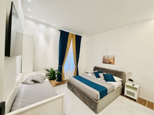 Camera tripla presso St Mary Major Loft, Roma con due letti, tende blu, TV e vista sul giardino