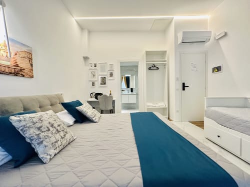 Moderna camera tripla presso St Mary Major Loft Roma con accenti blu, letti gemelli, armadio con specchio, bagno en-suite e aria condizionata
