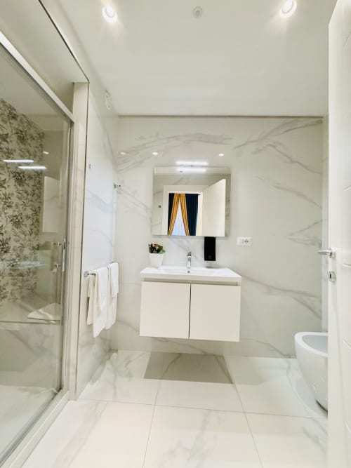 Bagno moderno del St Mary Major Loft Roma con pareti in marmo, vanità bianca, specchio, doccia e toilet