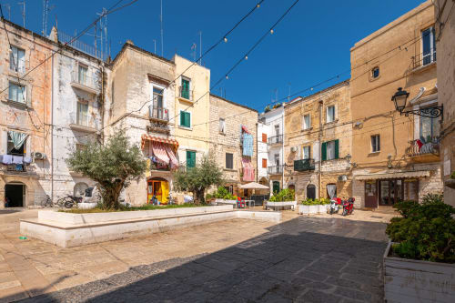 Piazza storica a Bari con architettura italiana tradizionale, ulivi e persiane colorate presso l'hotel Mas Collection