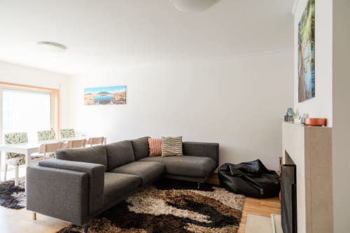 Sala de estar moderna com sofá cinza secional, piso de madeira e tapete estampado no apartamento EcoHost