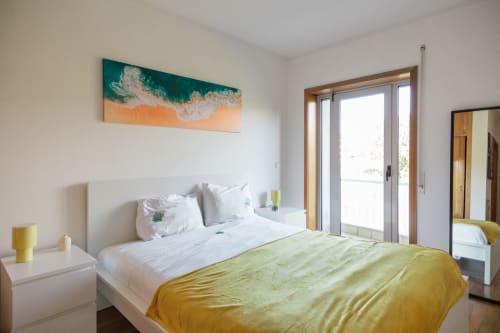 Quarto moderno e luminoso com manta amarela, roupa de cama branca, arte costeira em tons de azul-petróleo e portas de vidro abertas para o terraço em Gaia