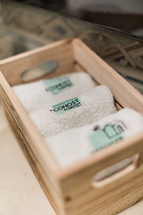 Amenidades EcoHost: produtos de banho em algodão com rótulos verdes em gaveta de madeira clara
