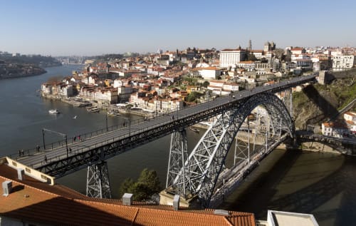 Icônica ponte de metal atravessando o rio Douro sobre a paisagem urbana do Porto com arquitetura tradicional, Portugal