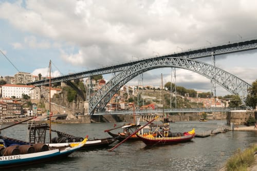 Ponte Dom Luís atravessando o rio Douro no Porto, Portugal com barcos tradicionais e edifícios coloridos nas encostas
