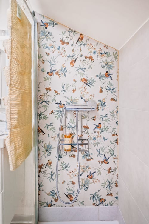 Parede do chuveiro com papel de parede botânico com pássaros e flores no apartamento de Lisboa do 1898 Home & Suites