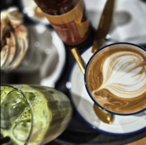 Specialty coffee with latte art at The Pink Cottage, Whitehead, alongside pastries and beverages