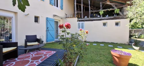 Cour ensoleillée de La Cour Des Saligues avec terrasse, fleurs colorées et coin détente à Riscle