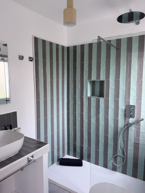 Baño moderno con paredes de ducha de azulejos rayados, alcachofa de lluvia, en apartamento de Corralejo