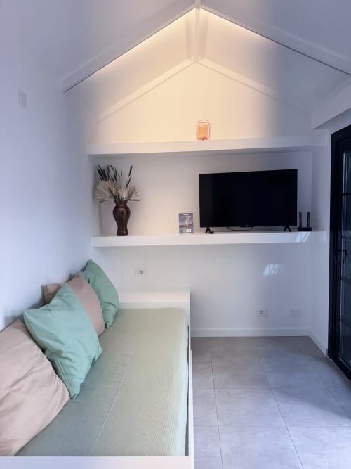 Moderno estudio en Kamalahouse con cama, sofá, TV en repisa mural y techo abovedado blanco en Corralejo