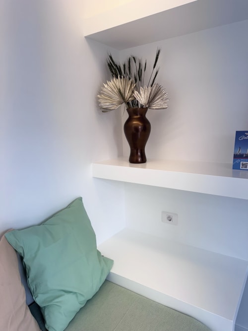 Estante moderno con jarrón oscuro, hierba de pampas seca y cojín verde en Kamalahouse, Corralejo