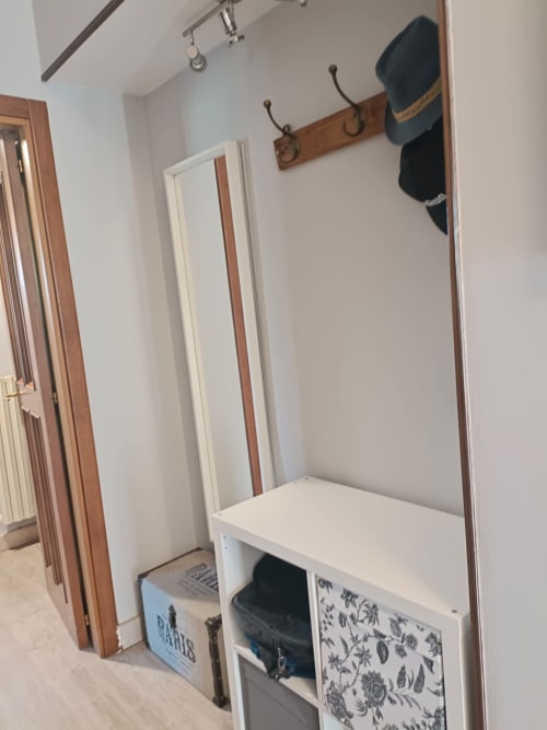 Modern entryway with white bench storage, wooden coat rack with hooks, and mirror at Tales of Abruzzo apartment in Atessa
