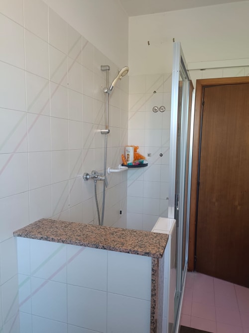 Modern shower in Atessa apartment with granite bench, white tile walls, and chrome fixtures at Tales of Abruzzo