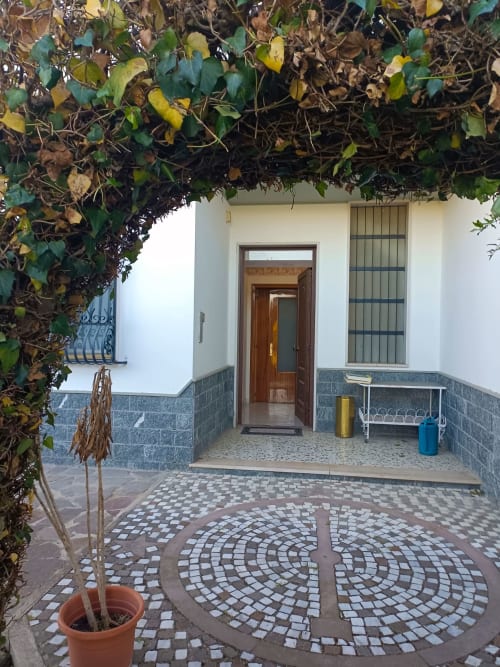 Ingresso della corte dell'hotel Tales of Abruzzo ad Atessa con pavimento a mosaico, arco ricoperto di edera e porta in legno