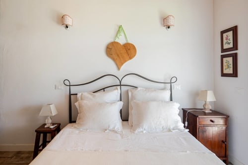 Elegant bedroom at Casa Rossi Roma with wrought iron bed, white linens, wooden nightstands, and floral wall art