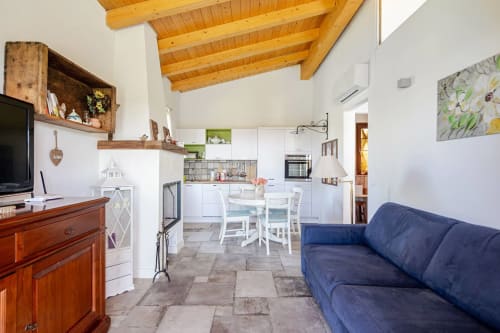 Open-plan living area at Casa Rossi Roma with blue sofa, white kitchen, wooden beams, and dining table