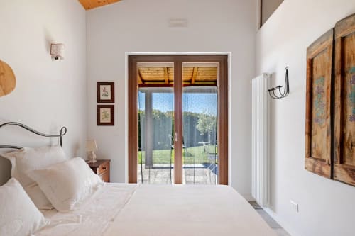 Bright bedroom at Casa Rossi Roma with white bedding, wooden doors opening to countryside views, and rustic decor
