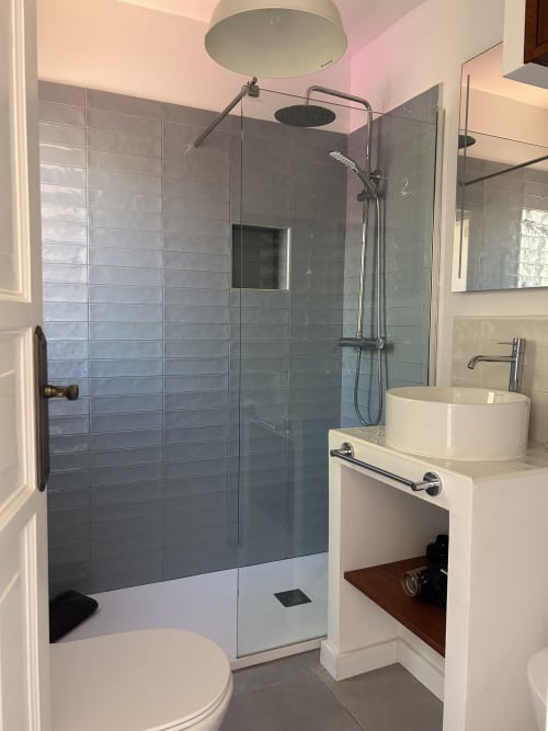 Baño moderno con ducha tipo spa, lavamanos blanco tipo recipiente, paredes de azulejos grises y accesorios cromados en apartamento Kamalahouse