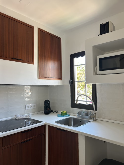 Cocina moderna en apartamento La Concha del Mar en Kamalahouse, Corralejo con muebles de madera, encimeras blancas y acero inoxidable