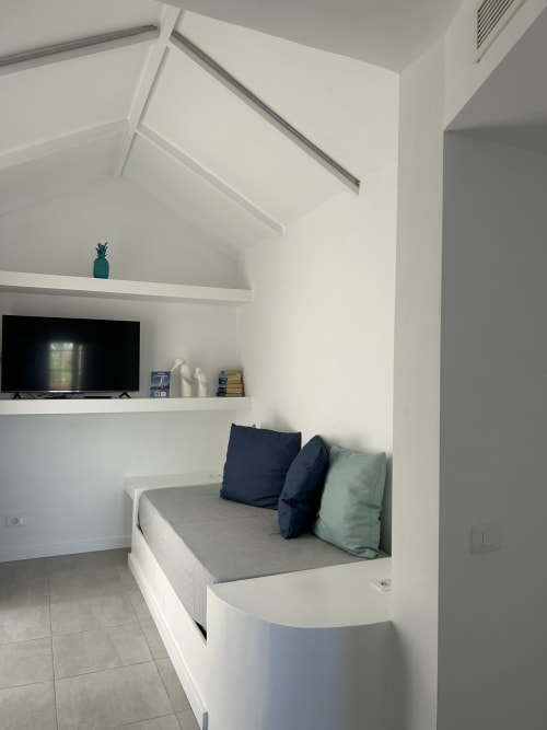 Moderno apartamento estudio con sofá cama blanco integrado, estantería para TV y claraboya en Corralejo