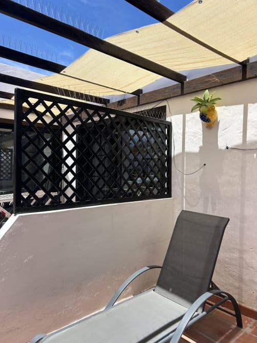 Terraza sombreada del apartamento Kamalahouse en Corralejo con tumbona y biombo de privacidad bajo toldo color crema