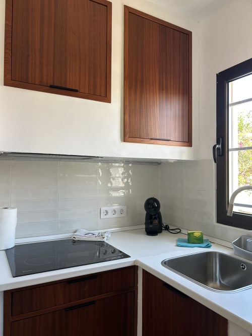 Cocina moderna en apartamento Kamalahouse SL Corralejo con muebles de madera, azulejos blancos tipo metro, placa de inducción