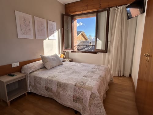 Bright individual bedroom at Hostal Estació in Puigcerdà with mountain views, wooden beams, and modern amenities