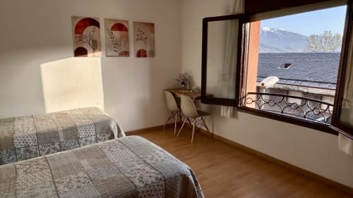 Bright triple room at Hostal Estació in Puigcerdà with twin beds, mountain views, desk, and modern furnishings