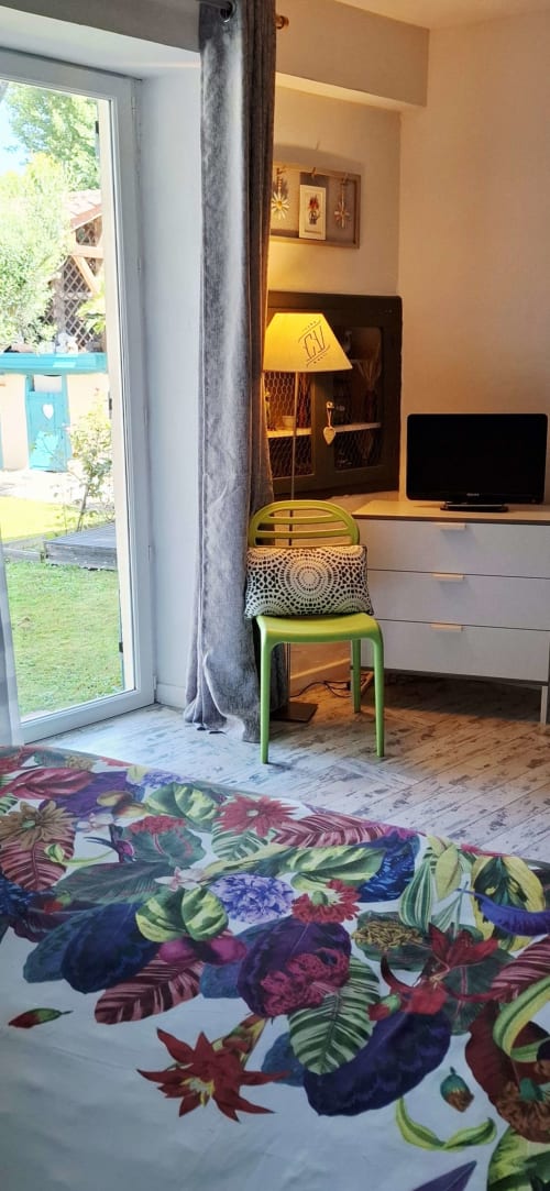 Espace de travail dans la chambre-jardin de La Cour Des Saligues à Riscle, avec bureau, télévision, lampe jaune et tapis floral coloré