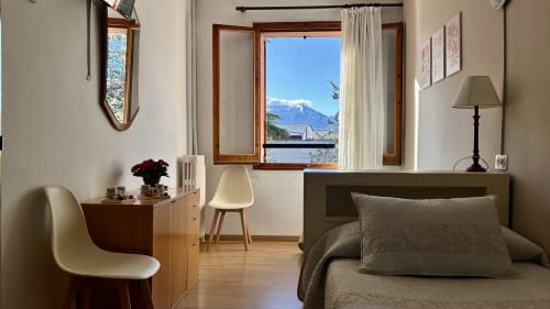 Modern hostel room at Hostal Estació in Puigcerdà with mountain views, desk, bed, and window overlooking snow-capped peaks