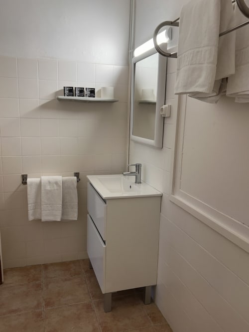 Modern bathroom in Hostal Estació with white sink vanity, mirror, towel rack, and tiled walls in Puigcerdà