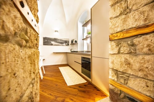 Nowoczesna kuchnia z kamiennymi ścianami i drewnianymi akcentami w apartamencie S'Incantu w Sardegna Explora House, Magomadas