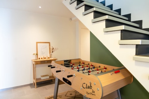 Salle de jeux Villa Rompsay avec baby-foot et console en bois sous l'escalier moderne de l'hôtel de La Rochelle