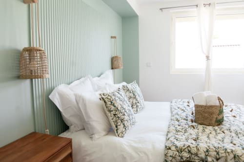 Chambre moderne et lumineuse à la Villa Rompsay ARLOÉ, La Rochelle, avec mur d'accent vert menthe, literie blanche, coussins botaniques