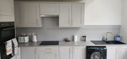 Modern kitchen in Radcliffe N6 apartment with white cabinets, gray subway tile backsplash, black appliances, and washing