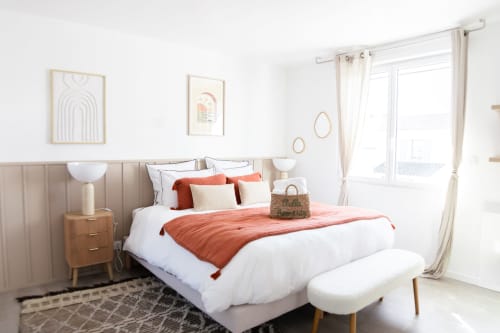 Chambre lumineuse et moderne de la villa ARLOÉ La Rochelle, avec accents corail, literie blanche et lumière naturelle par portes vitrées