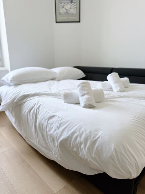 Literie blanche impeccable avec serviettes roulées sur le lit à l'appartement ARLOÉ Le Rochelois, La Rochelle