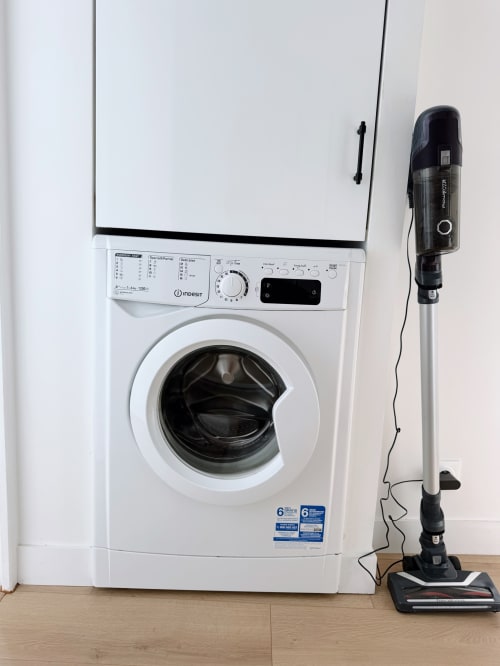 Machine à laver Indesit blanche avec aspirateur dans un appartement à La Rochelle