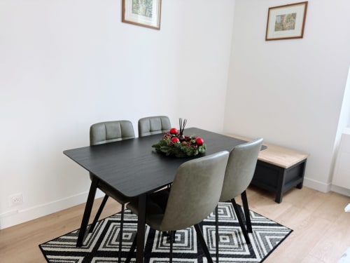Salle à manger moderne de l'appartement ARLOÉ à La Rochelle avec table noire, chaises grises et décoration festive