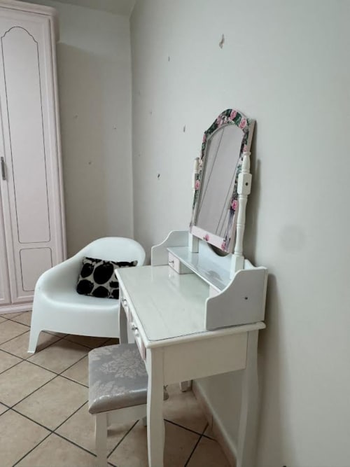 Penteadeira branca com espelho floral no quarto do apartamento B&B em Catania, com banqueta redonda e almofada decorativa