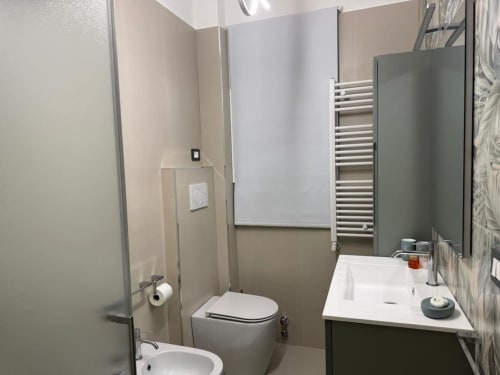 Banheiro moderno em apartamento em Catania com vaso sanitário, pia, toalheiro aquecido e box de chuveiro