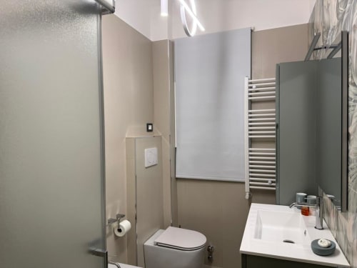 Banheiro moderno do apartamento B&B em Catania com vaso sanitário, pia branca, aquecedor de toalhas e box de ducha