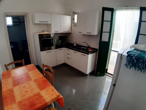 Cucina e zona pranzo moderna dell'appartamento Santa Cesarea Vacanze con mobili bianchi, piani neri e arancione