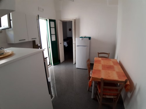 Zona cucina-soggiorno dell'appartamento Santa Cesarea Vacanze con tavolo, frigorifero e attrezzature per cucinare