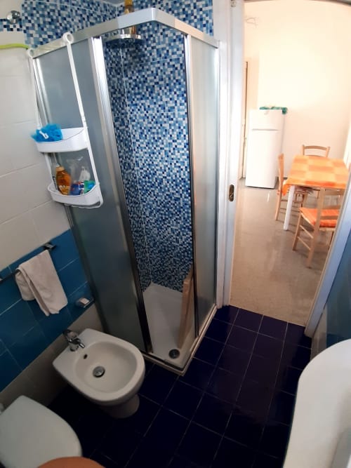 Bagno moderno con doccia in mosaico blu all'appartamento Santa Cesarea Vacanze, con lavabo e pavimento in piastrelle nere