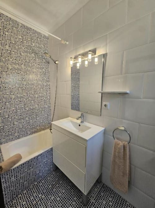 Baño moderno de Villa Palmer Paguera con tocador blanco, detalles de azulejos de mosaico, espejo iluminado y bañera con ducha