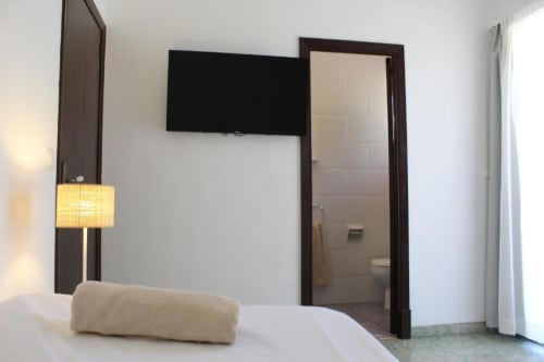 Habitación moderna en Villa Palmer de Paguera con TV de pantalla plana, lámpara y baño privado con puerta de marco de madera oscura