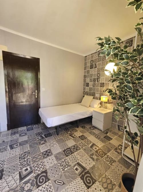 Habitación individual deluxe del hostal Villa Palmer Paguera con cama de matrimonio, azulejos estampados, puerta oscura y enredadera